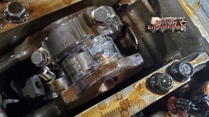 A crankshaft in a block with damaged engine bearings on it.