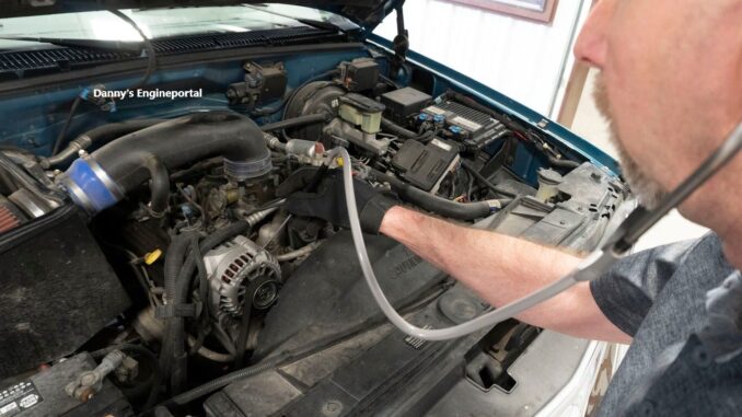 A mechanic using a diagnostic stethoscope to pinpoint a noise.