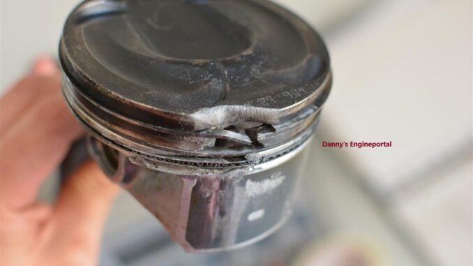 Close up of a damaged engine piston with pitting and cracks caused by detonation.