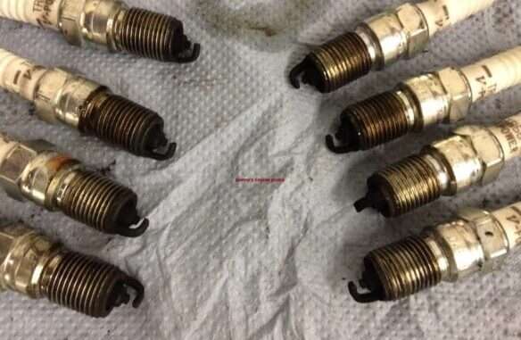 Close up of a spark plug tip soaked in gasoline due to engine flooding.